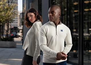 A man and a woman with off-white quarter-zip windbreakers standing next to eachother in the city